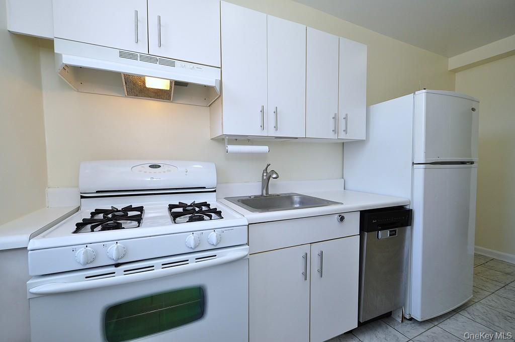 142 Garth Road, Unit 4A Scarsdale, NY 10583 - Photo 9 of 44 a white kitchen with stove and white cabinets