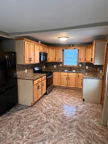 a kitchen with stainless steel appliances granite countertop a stove a sink dishwasher a refrigerator and a microwave