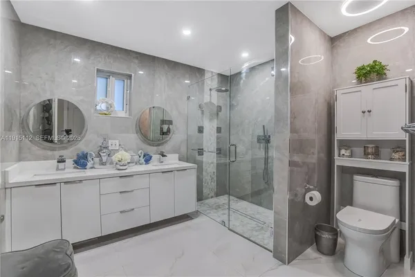 a bathroom with a toilet a sink a mirror a shower and vanity