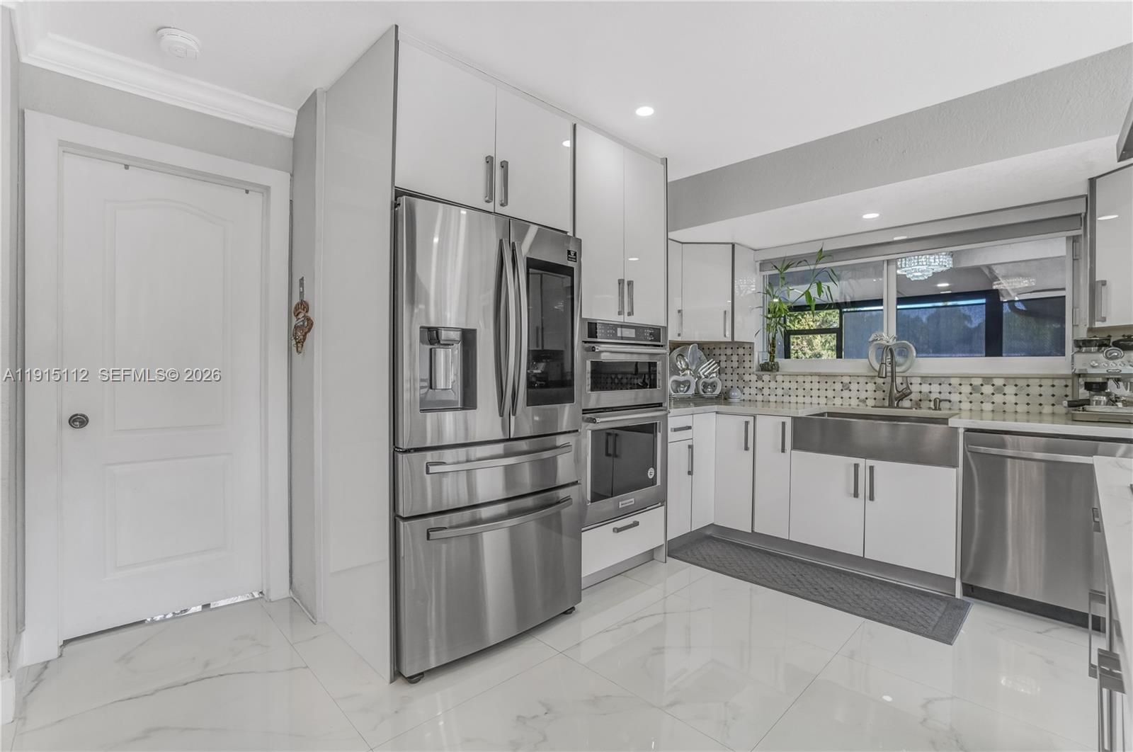 12601 Southwest 204th Street Miami, FL 33177 - Photo 6 of 40 a kitchen with white cabinets and stainless steel appliances