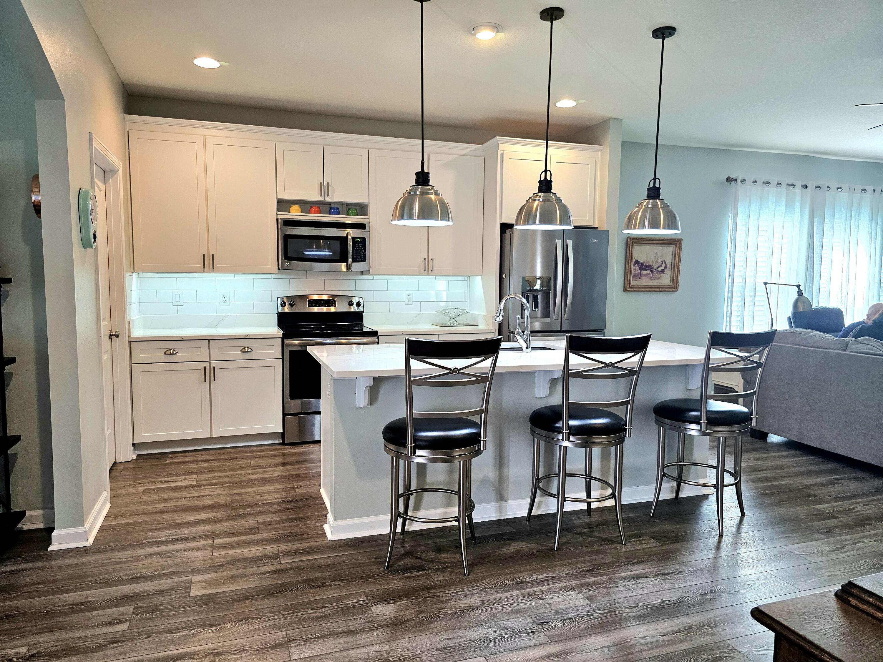 140 Nelly Street Freeport, FL 32439 - Photo 7 of 53 a kitchen with stainless steel appliances granite countertop a stove top oven a refrigerator a dining table and chairs with wooden floor