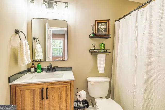 a bathroom with a granite countertop toilet sink and mirror