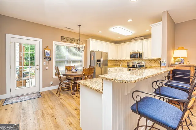 a view of a kitchen with kitchen island granite countertop lots of counter top space a sink and appliances