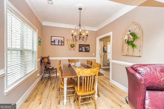 a view of a dining room with furniture a chandelier and wooden floor