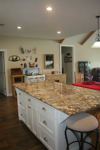 a room with kitchen island granite countertop furniture and a flat screen tv