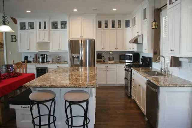 a kitchen with stainless steel appliances granite countertop a stove top oven a sink refrigerator and cabinets