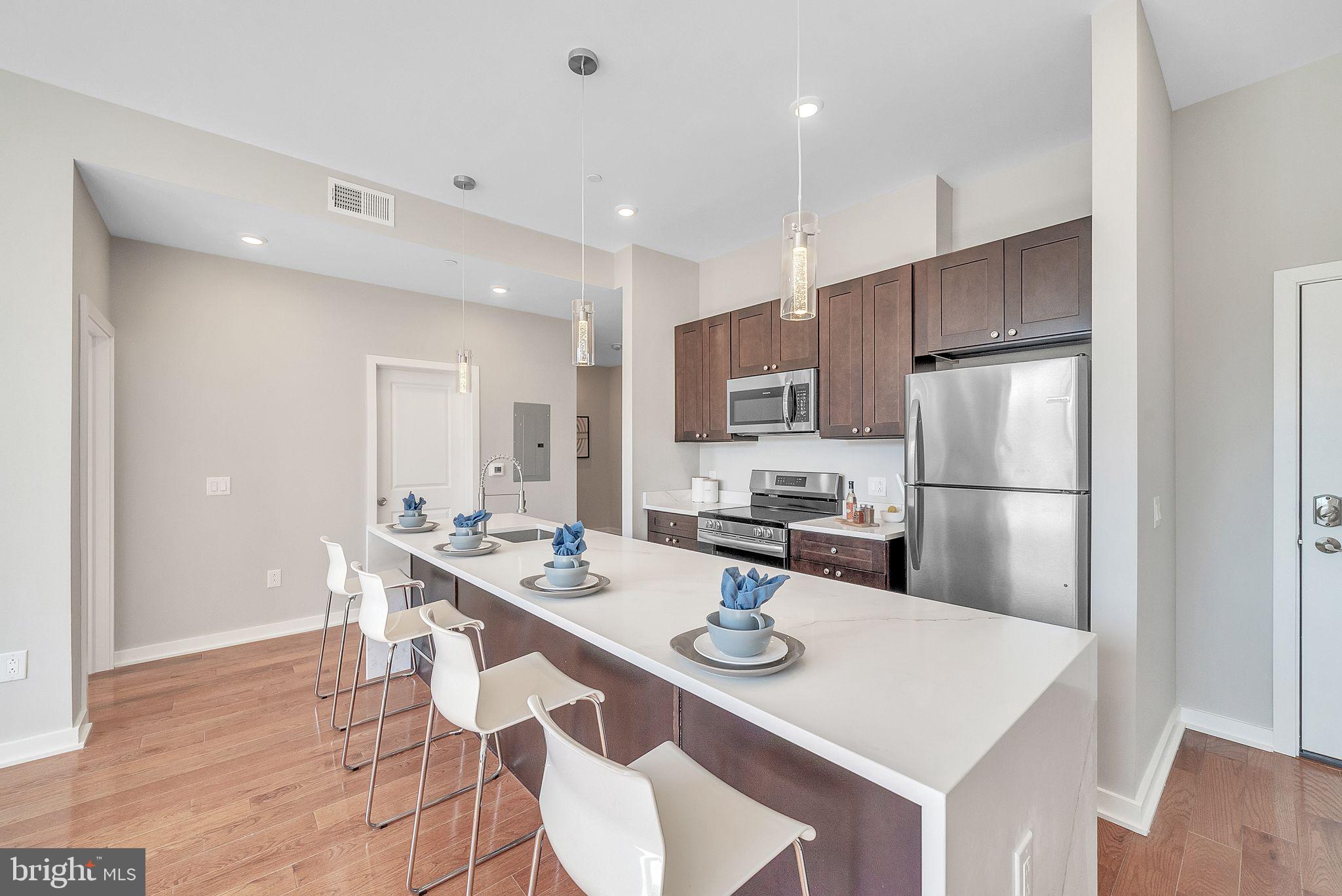 100 Forrest Avenue, Unit 204 Narberth, PA 19072 - Photo 7 of 17 a kitchen with a sink a kitchen island and stainless steel appliances