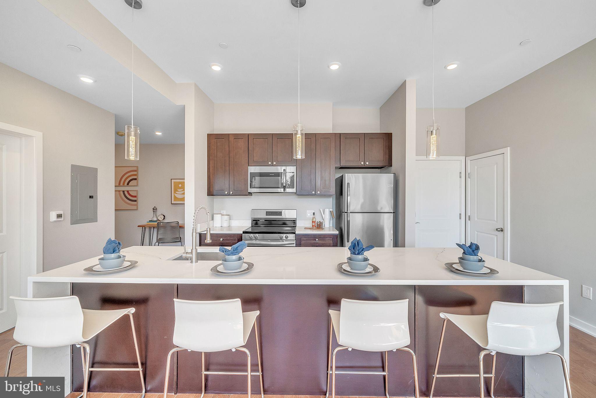 100 Forrest Avenue, Unit 204 Narberth, PA 19072 - Photo 9 of 17 a kitchen with stainless steel appliances kitchen island granite countertop a dining table chairs and a refrigerator
