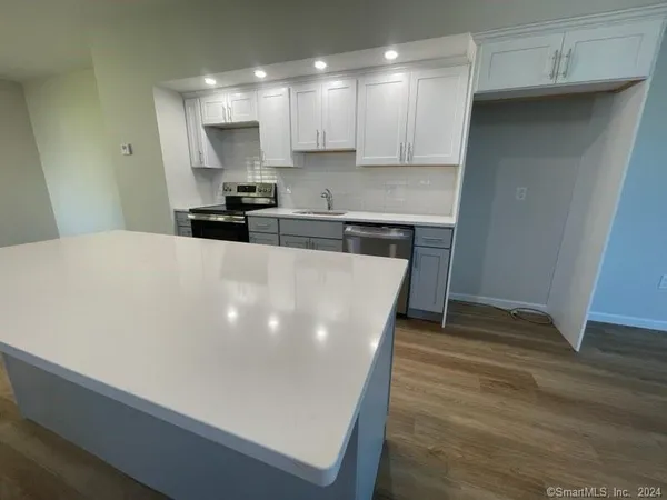 a large kitchen with stainless steel appliances a refrigerator a sink a stove a microwave and cabinets