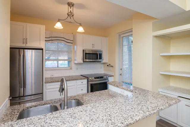 a kitchen with granite countertop a sink a stove and cabinets