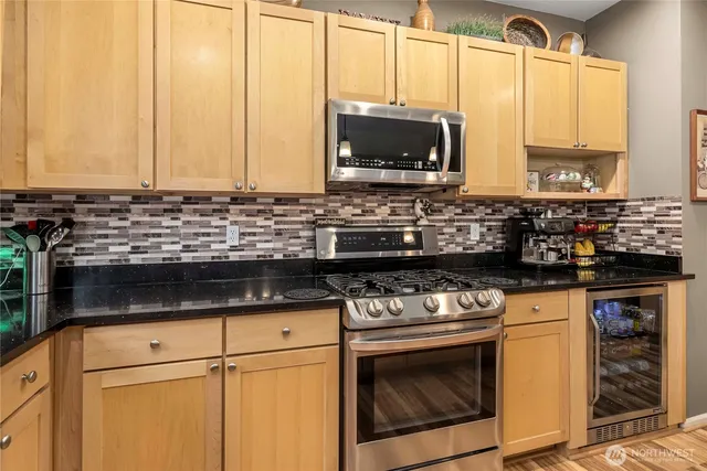 a kitchen with stainless steel appliances granite countertop a stove a sink and a microwave