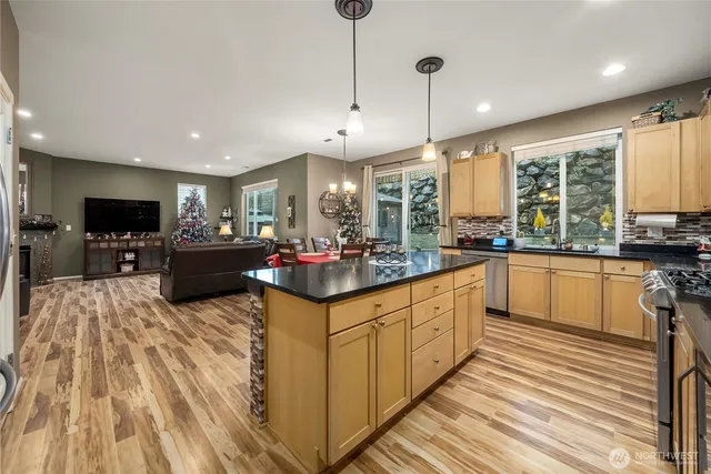 a kitchen with stainless steel appliances kitchen island granite countertop a sink counter space a large window and a fireplace