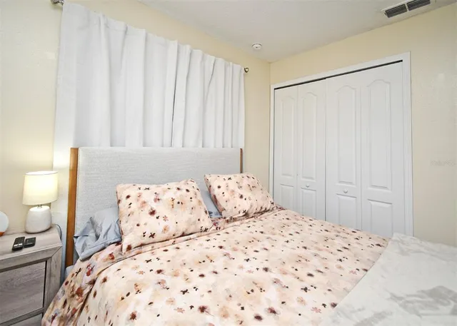 a bedroom with a large bed and a lamp on dresser