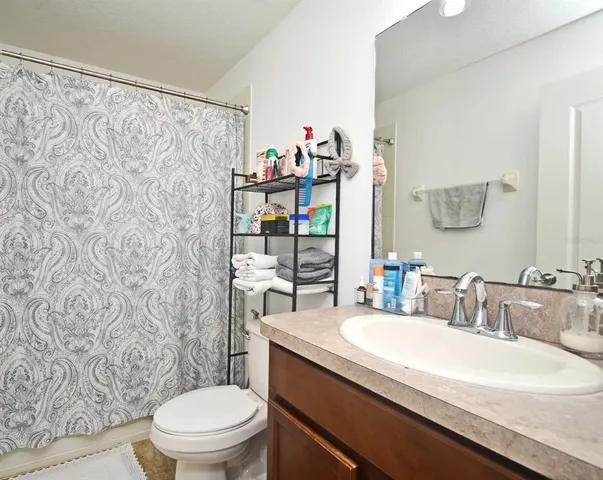 a bathroom with a granite countertop sink a toilet and a shower curtain