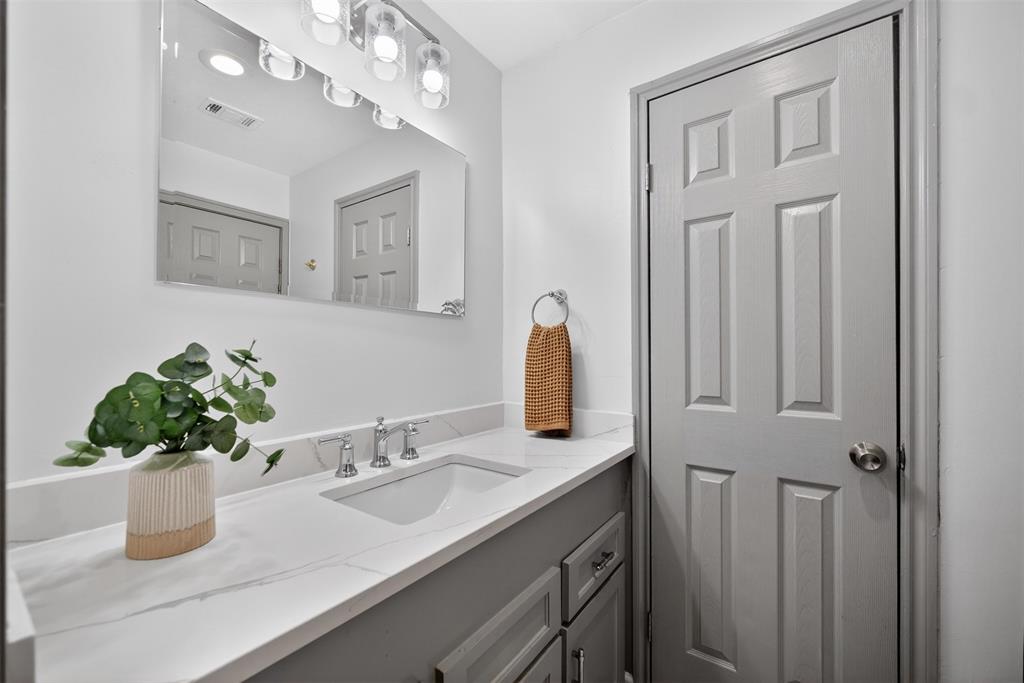 9660 Timberleaf Drive Dallas, TX 75243 - Photo 31 of 40 Bathroom vanity featuring a single undermount sink, a white countertop with subtle veining, and a chrome-finish faucet