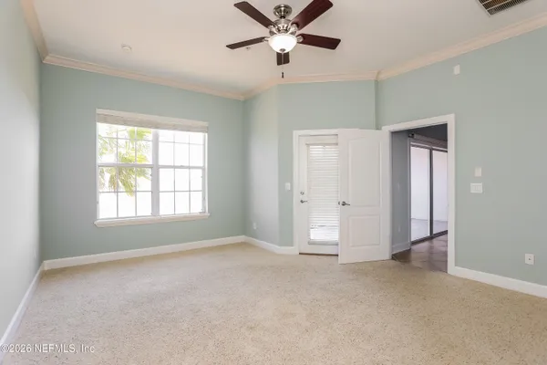 a view of a livingroom with a ceiling fan & windows