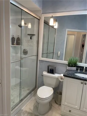 a bathroom with a toilet a sink and glass door shower