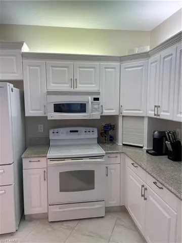a kitchen with white cabinets and white appliances