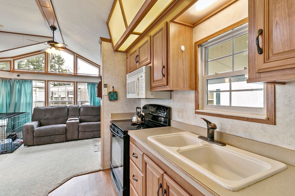 404 Southwick Road, Unit 9 Westfield, MA 01085 - Photo 15 of 30 a kitchen with stainless steel appliances granite countertop a sink a stove and a dining table with large windows