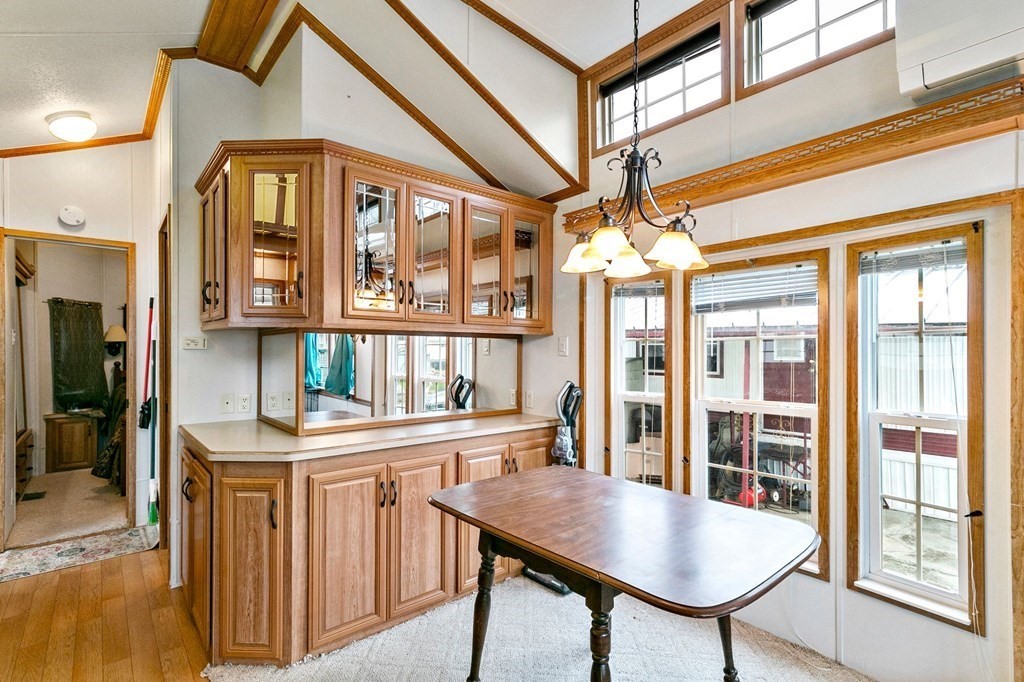 404 Southwick Road, Unit 9 Westfield, MA 01085 - Photo 9 of 30 a dining room with wooden floor a chandelier a wooden table and chairs