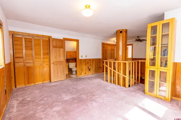 a view of an empty room with wooden floor and fan
