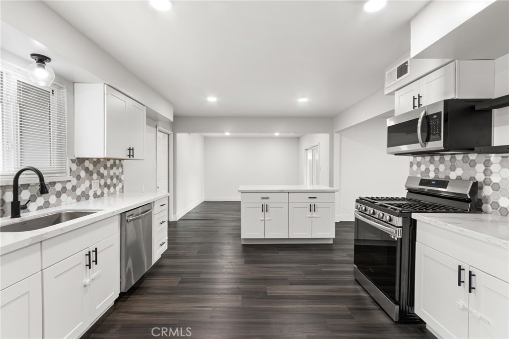 2618 Hoover Court Merced, CA 95340 - Photo 7 of 30 a kitchen with stainless steel appliances a stove top oven a sink a refrigerator white cabinets and wooden floor