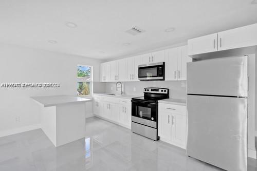 655 Southwest 5th Street Homestead, FL 33030 - Photo 5 of 23 a kitchen with white cabinets and stainless steel appliances
