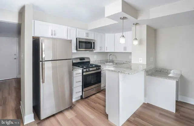 a kitchen with cabinets stainless steel appliances and wooden floor