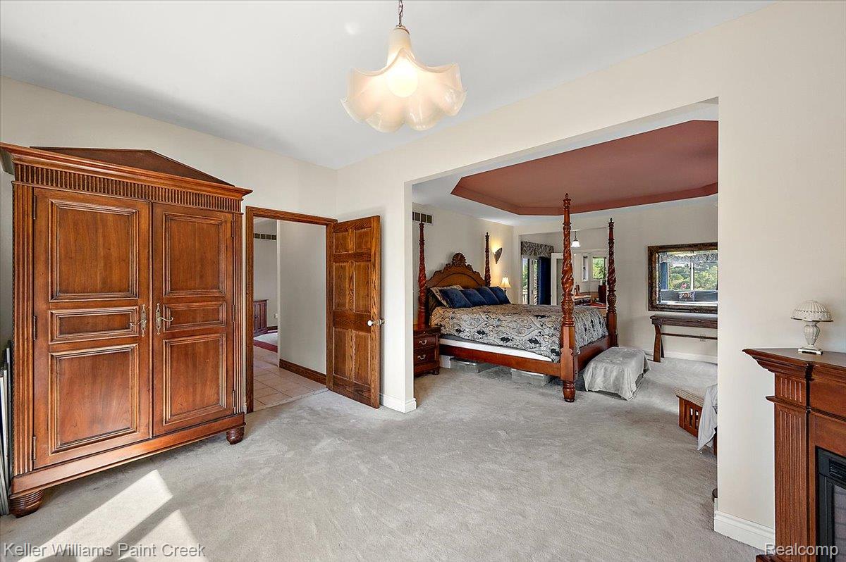 69069 Campground Road Romeo, MI 48065 - Photo 42 of 78 Carpeted room featuring a recessed ceiling with a burgundy paint finish, a four-poster wood bed frame, and an attached fireplace with a wood mantle