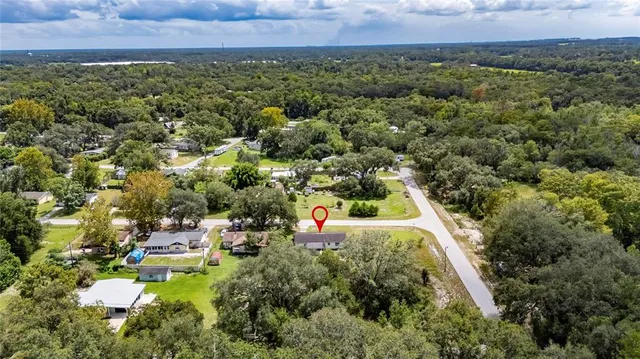 an aerial view of residential houses with outdoor space and trees