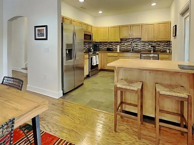 a view of a kitchen with kitchen island a stove a refrigerator cabinets dining table and chairs