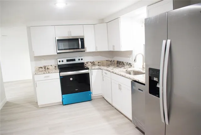 a kitchen with stainless steel appliances granite countertop a stove a sink and a microwave