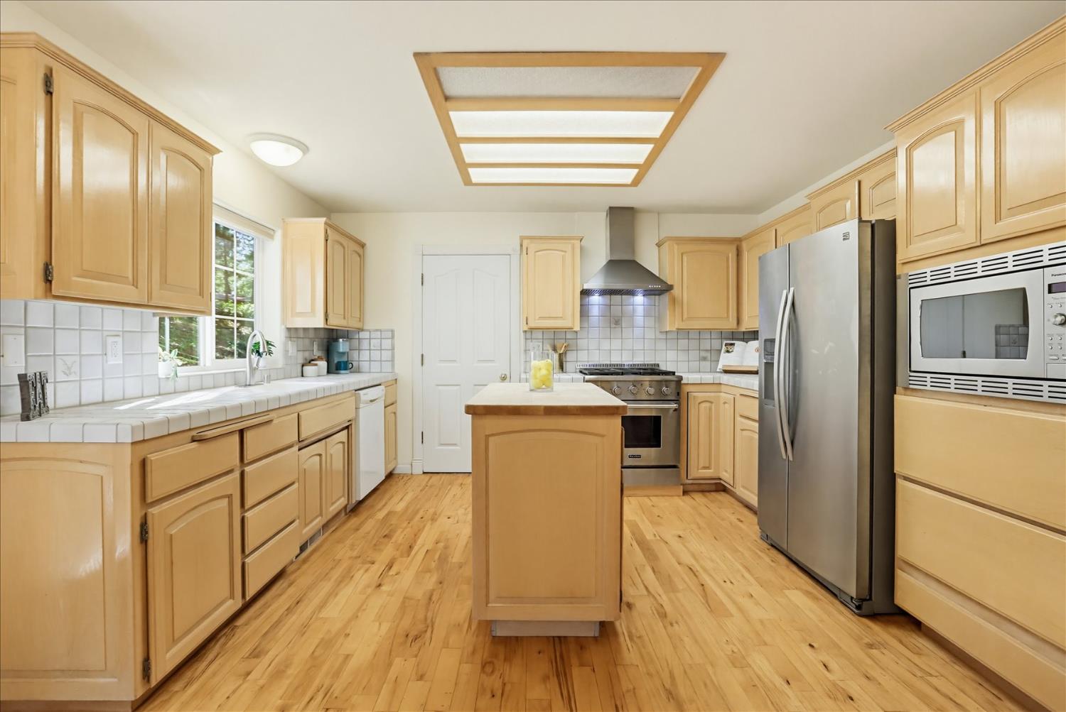 21324 Oak Ridge Drive Grass Valley, CA 95945 - Photo 11 of 32 a kitchen with a refrigerator a sink dishwasher with a stove and wooden floor