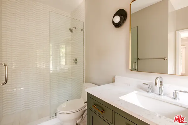 a bathroom with a granite countertop sink a mirror and a shower