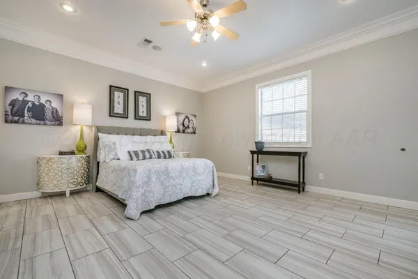 a spacious bedroom with a bed a couch and a flat tv screen on dresser