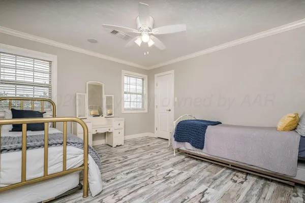 a bedroom with a bed and a dresser with wooden floor