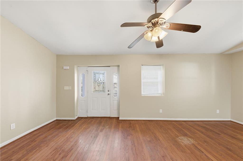 94 Ericson Street Southeast Atlanta, GA 30317 - Photo 6 of 39 an empty room with wooden floor chandelier fan and windows