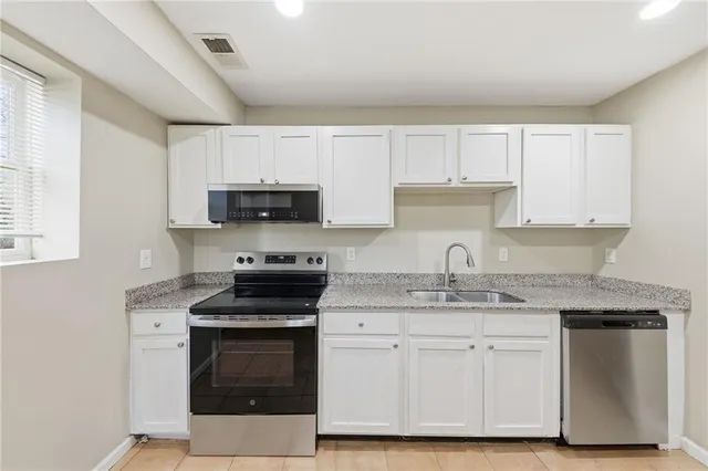 a kitchen with stainless steel appliances granite countertop a stove a sink and white cabinets