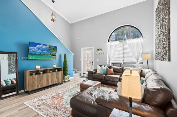 a living room with furniture a flat screen tv and a floor to ceiling window