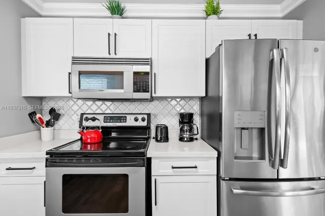 a kitchen with appliances a refrigerator and cabinets