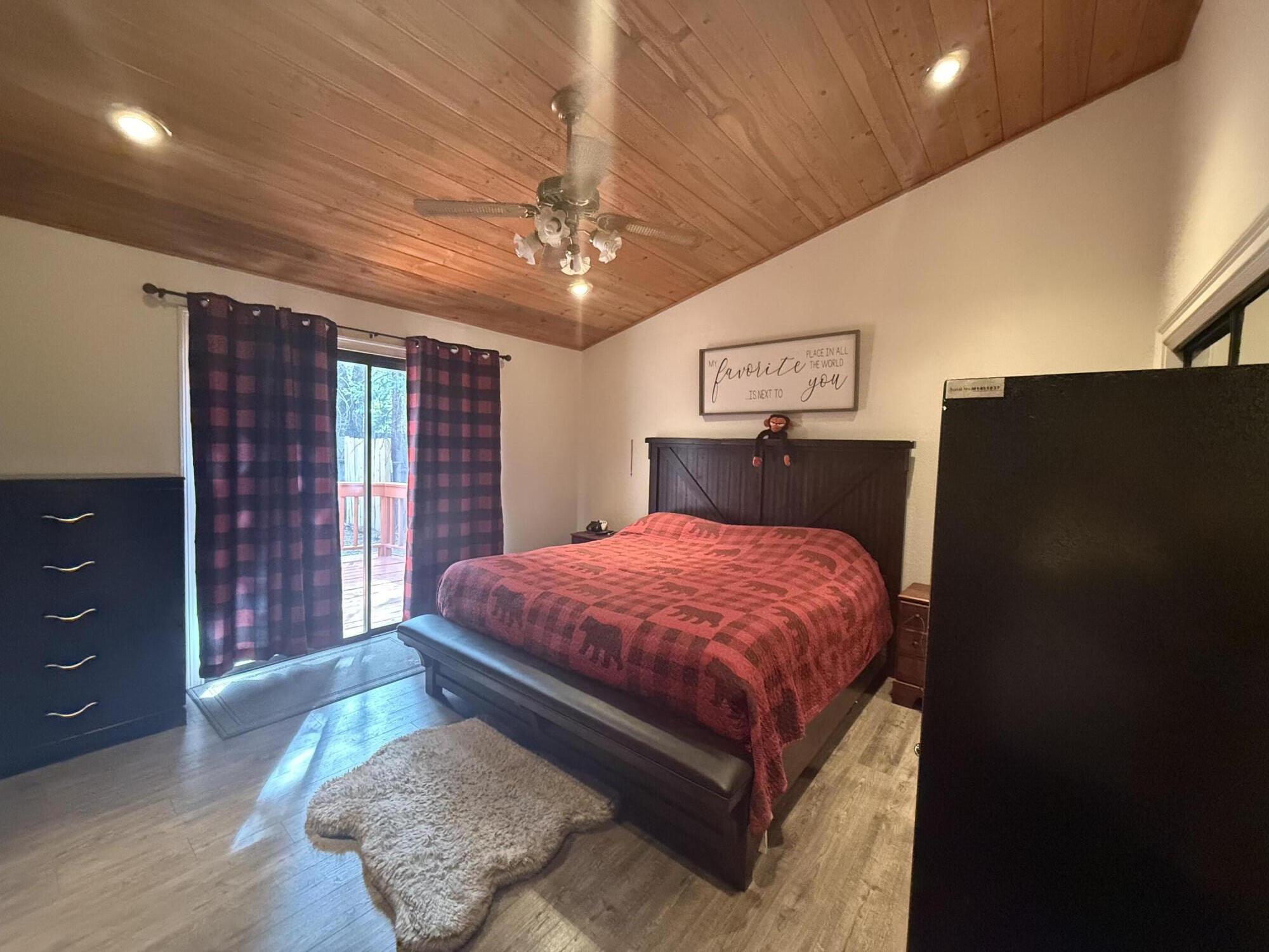 7097 Shasta Forest Drive Shingletown, CA 96088 - Photo 20 of 44 a spacious bedroom with a bed and a chandelier