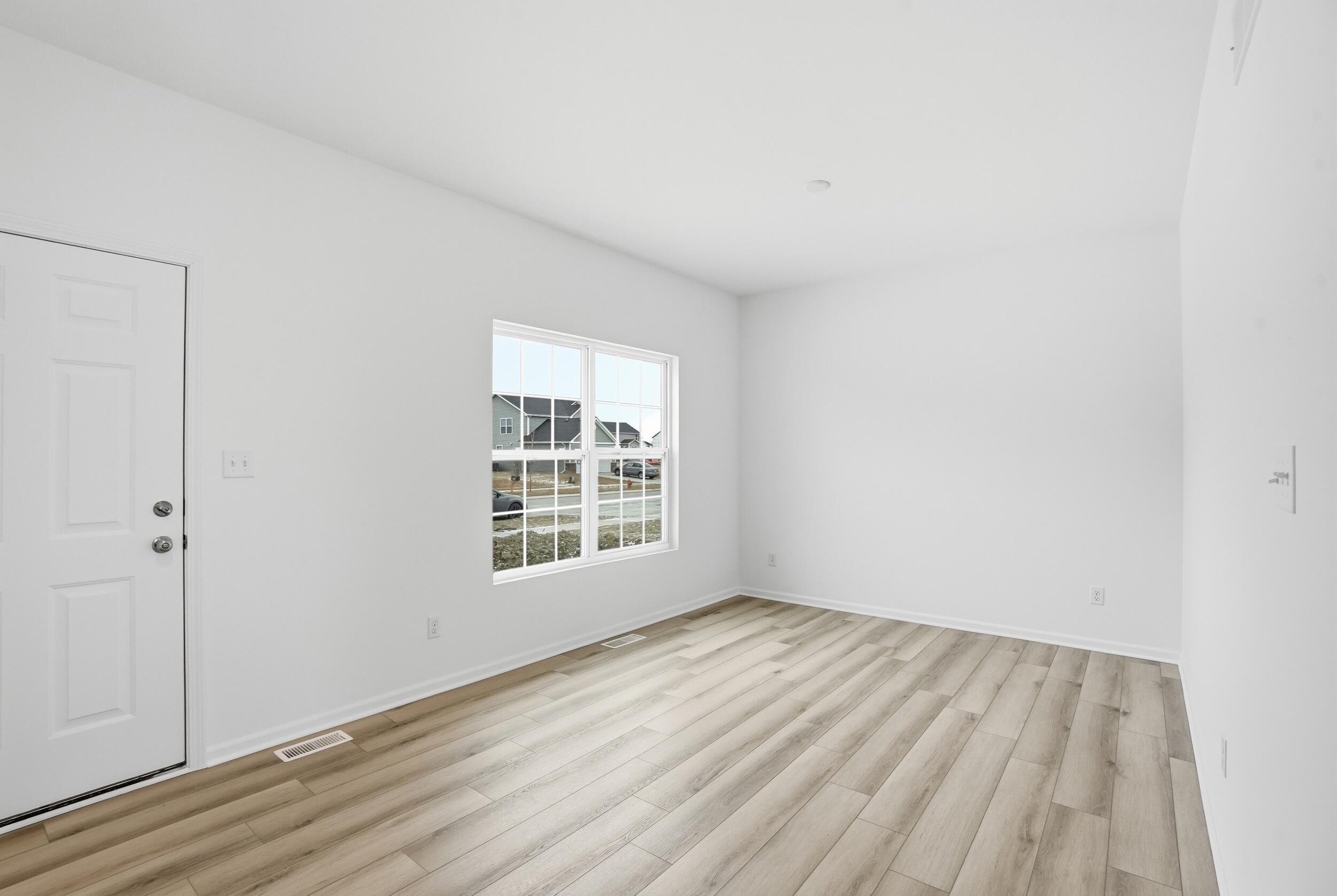 6587 East 104th Avenue Winfield, IN 46307 - Photo 3 of 34 an empty room with wooden floor and windows