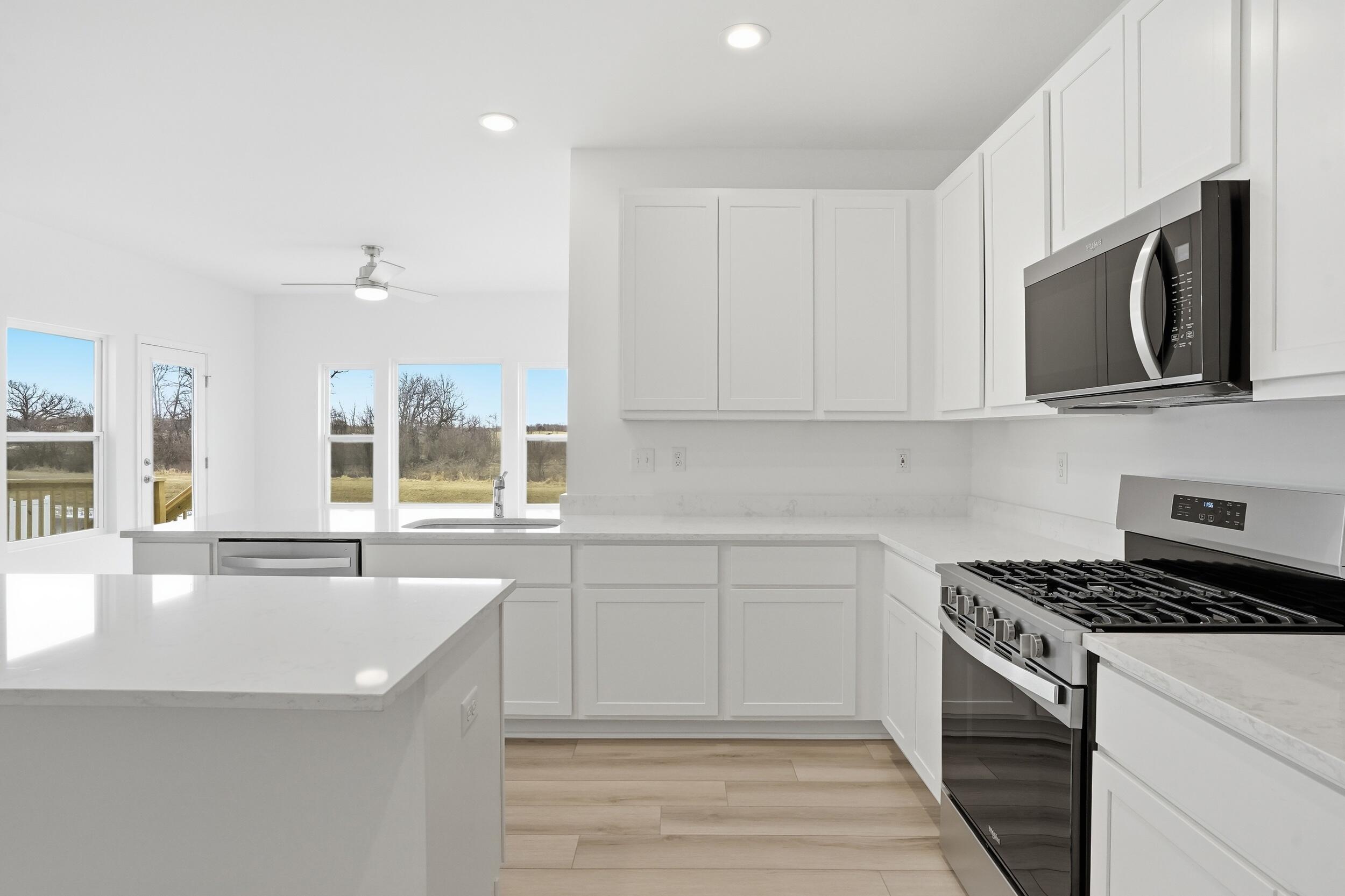 6587 East 104th Avenue Winfield, IN 46307 - Photo 10 of 34 a kitchen with stainless steel appliances granite countertop a sink and a stove top oven with white cabinets