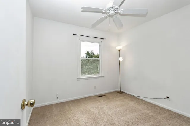 an empty room with a window and a fan