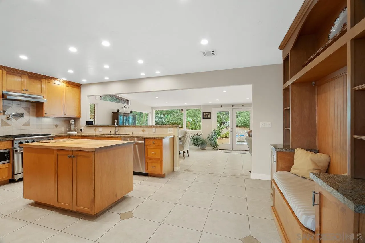11116 Morning Dove Road Lakeside, CA 92040 - Photo 11 of 60 a large kitchen with kitchen island a large counter top space a sink a stove a refrigerator a counter top space and a large window