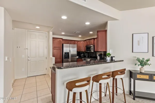 a kitchen with stainless steel appliances kitchen island granite countertop a refrigerator and a counter space