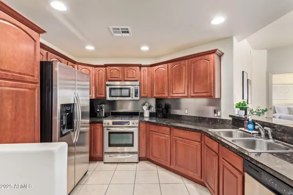 a kitchen with stainless steel appliances granite countertop a sink stove refrigerator and cabinets