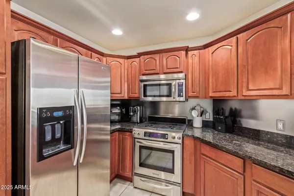 a kitchen with stainless steel appliances granite countertop a refrigerator a stove and a sink with wooden floor
