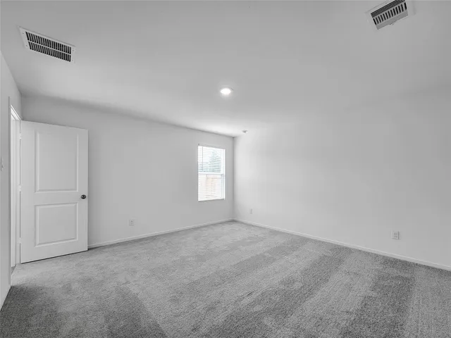a view of an empty room with a window and a bathroom