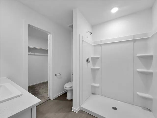 a bathroom with a granite countertop sink a toilet and shower